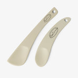 UpCircle cosmetic spatulas resting on a textured cream travertine surface, showcasing a minimal, reusable design.