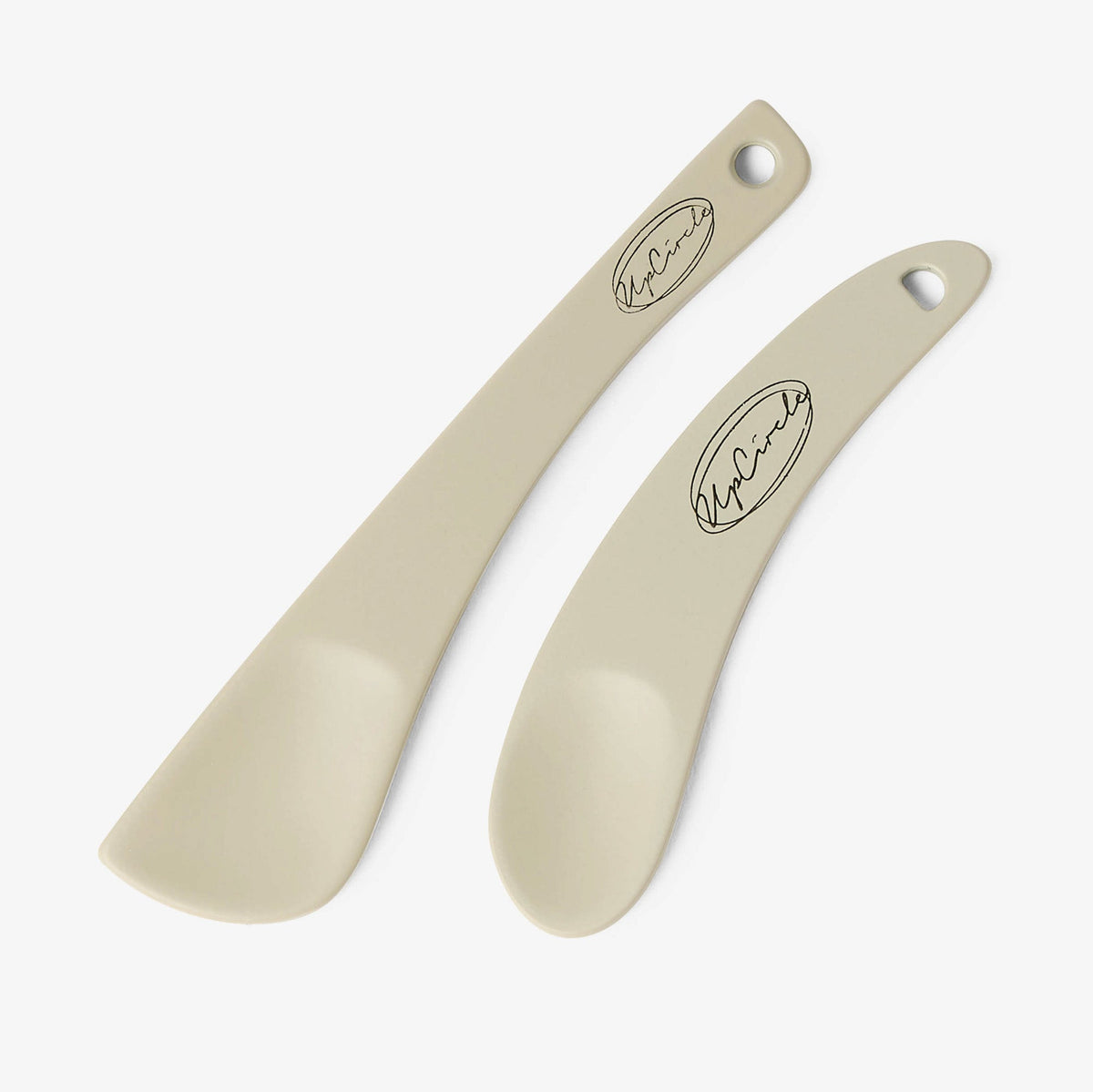 UpCircle cosmetic spatulas resting on a textured cream travertine surface, showcasing a minimal, reusable design.