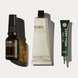 YCODE The Advanced Routine skincare set displayed in sleek, minimalist white containers on a textured travertine plinth.