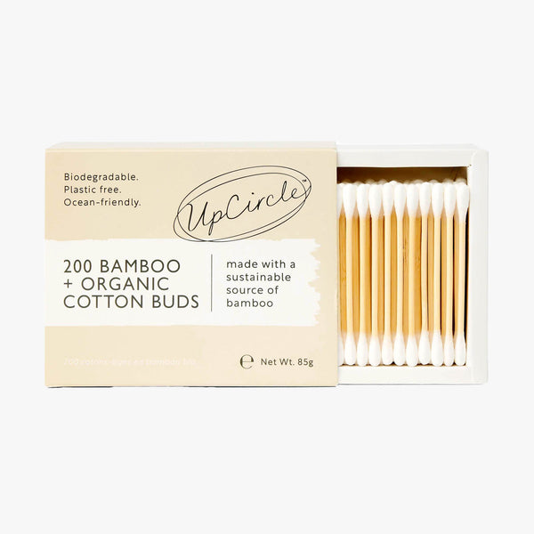 UpCircle organic bamboo cotton buds packaged in a minimalist eco-friendly container resting on a travertine surface.