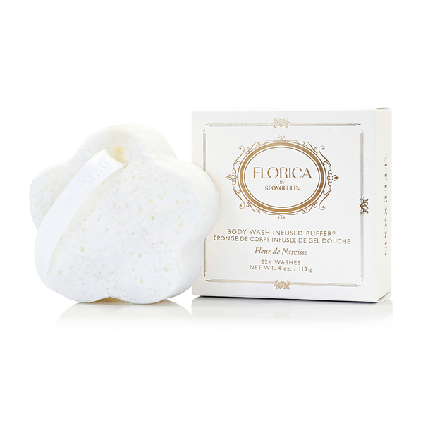 Spongellé Fleur de Narcisse Body Buffer featuring a delicate floral-embossed sponge texture, presented on a stone plinth.