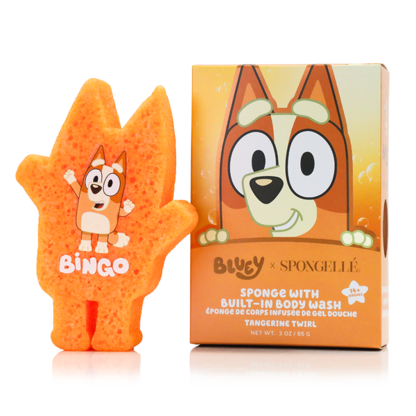 Spongellé Bingo Tangerine Twirl body buffer sponge in a bright orange citrus-inspired circular shape on a stone plinth.