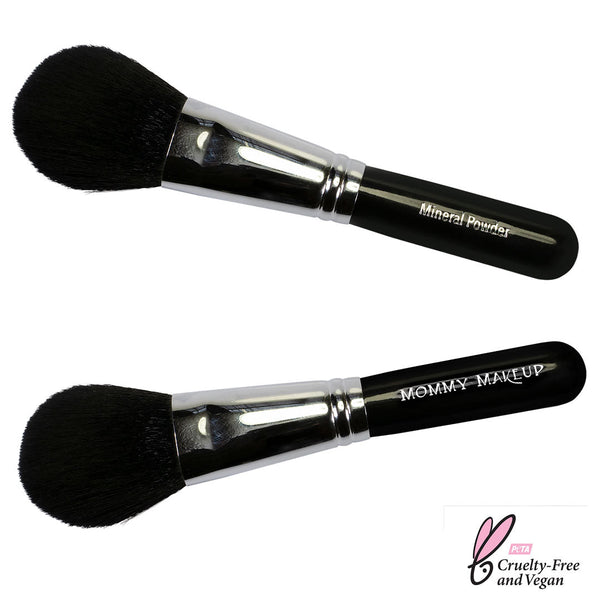 Mommy Makeup travel-sized mineral powder brush resting on a smooth beige travertine stone in soft morning light.