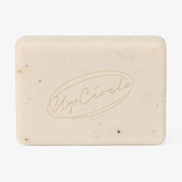 UpCircle Fennel + Cardamom Chai Cleansing Bar resting on a textured cream ceramic soap dish with minimalist branding.