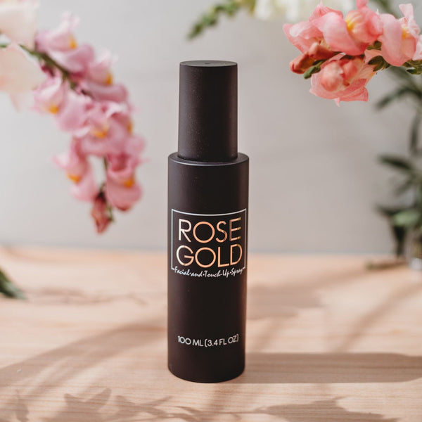 Rose Gold Sunless Facial Tanning Mist in a sleek, minimalist translucent bottle resting on a textured travertine plinth.