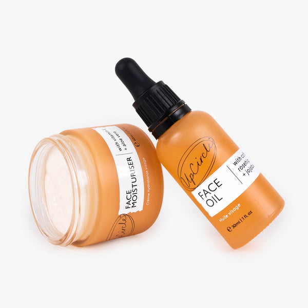UpCircle Hydration Skincare Set featuring glass serum and cream jars arranged on a minimalist beige travertine plinth.