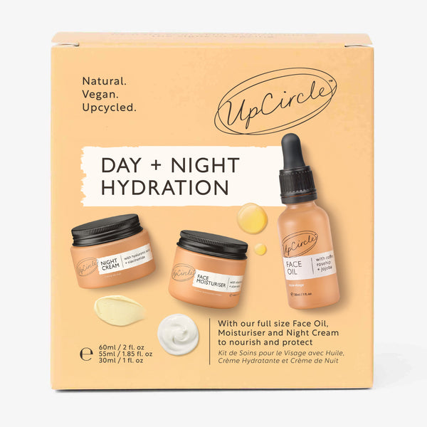 UpCircle Day + Night Hydration Set featuring glass serum and cream jars arranged on a textured stone surface.