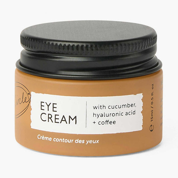 UpCircle Eye Cream in a minimalist glass jar resting on a smooth travertine plinth next to folded oatmeal linen.