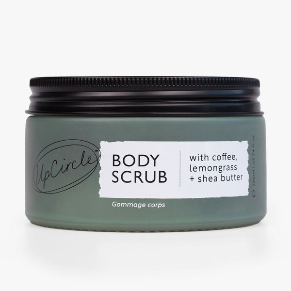 UpCircle Coffee Body Scrub in a sustainable glass jar, set against a textural travertine surface with neutral linen.