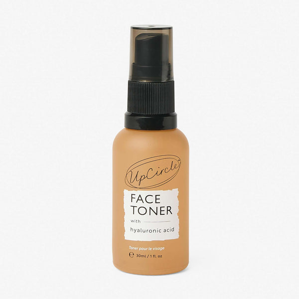 UpCircle Face Toner with Hyaluronic Acid in a sustainable glass travel-size bottle, resting on textured travertine.