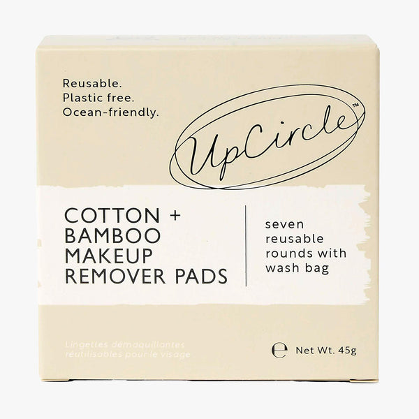 UpCircle bamboo and cotton reusable makeup pads stacked neatly on a textured travertine plinth against champagne linen.