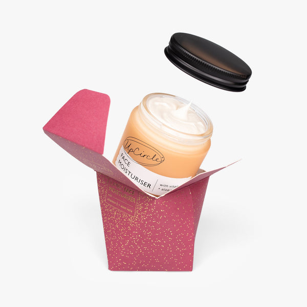 UpCircle Face Moisturizer with Vitamin E in a jumbo glass jar, captured on a textured travertine plinth.