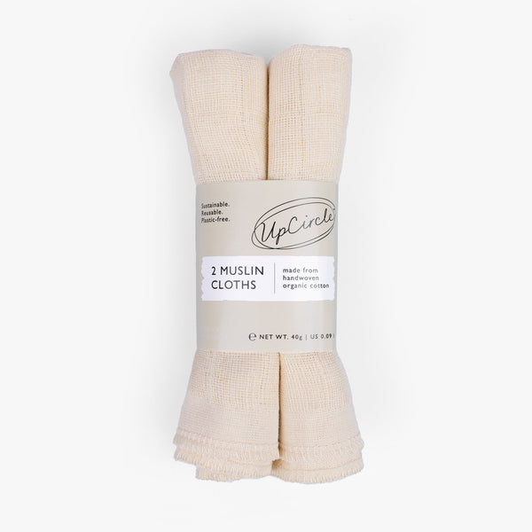 UpCircle organic muslin face cloths neatly folded on a travertine surface, embodying a clean and minimalist aesthetic.