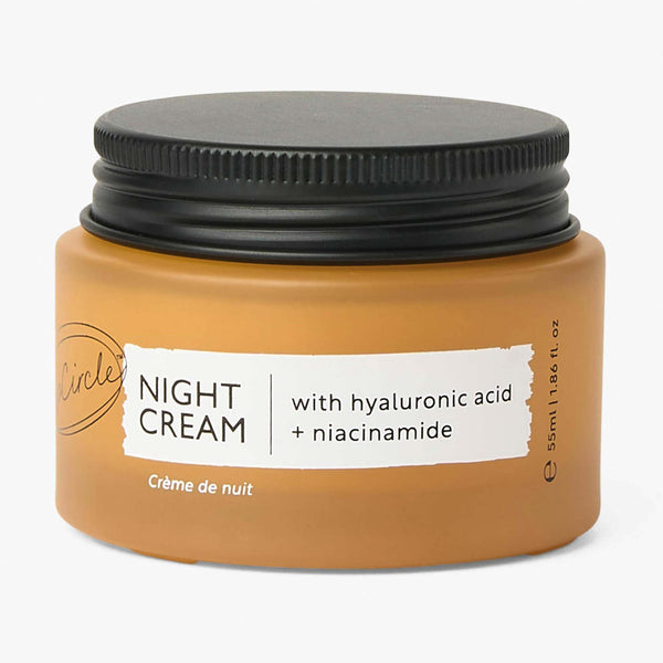 UpCircle Night Cream with Hyaluronic Acid and Niacinamide in a minimalist glass jar on a smooth travertine plinth.