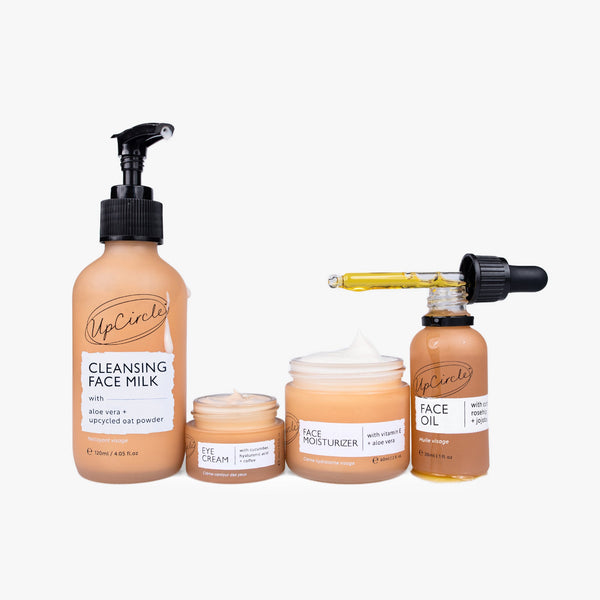 UpCircle Sensitive Skin Bundle featuring glass serum and cream bottles on a textured travertine plinth, minimalist style.