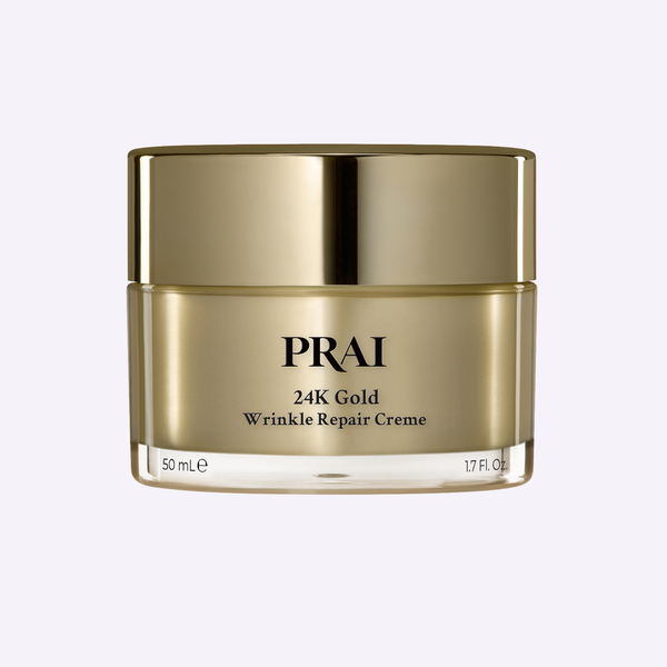 PRAI Beauty 24K Gold Wrinkle Repair Creme in a metallic gold jar, elegantly resting on a textured oatmeal linen cloth.