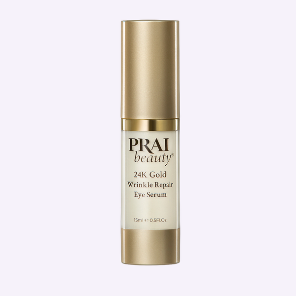 PRAI Beauty 24K Gold Wrinkle Repair Eye Serum in a sleek gold-accented bottle resting on a textured stone surface.