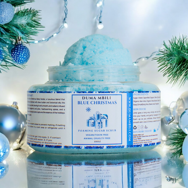 Adorn Collective Blue Christmas Foaming Sugar Scrub in a premium glass jar, set against a textural travertine backdrop.