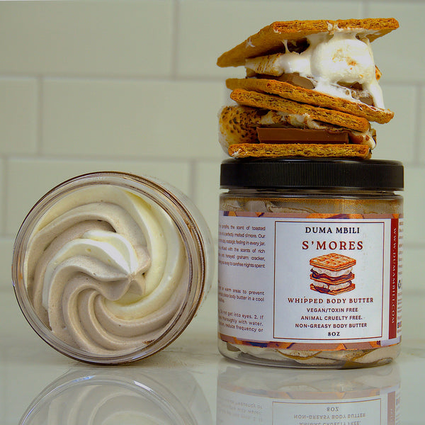 Adorn Collective S’mores Whipped Body Butter in an elegant glass jar, displayed on a textured travertine plinth.