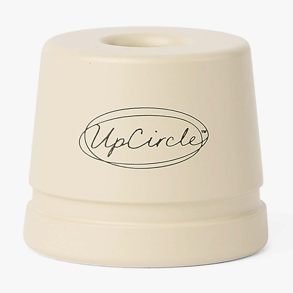 UpCircle safety razor stand displayed on a textured travertine plinth against a backdrop of soft oatmeal raw silk.