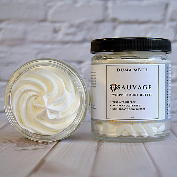 Adorn Collective Sauvage Whipped Body Butter in a minimalist glass jar resting on a textured travertine surface.