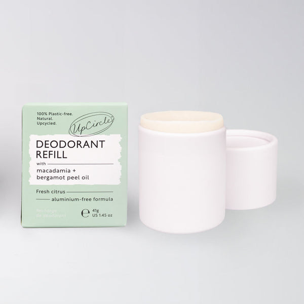 UpCircle deodorant refill tester in a minimalist paper tube, set against a smooth beige travertine surface.