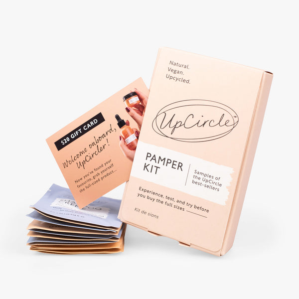 UpCircle Pamper + Gift skincare kit arranged on a textured travertine surface with minimalist, eco-conscious packaging.
