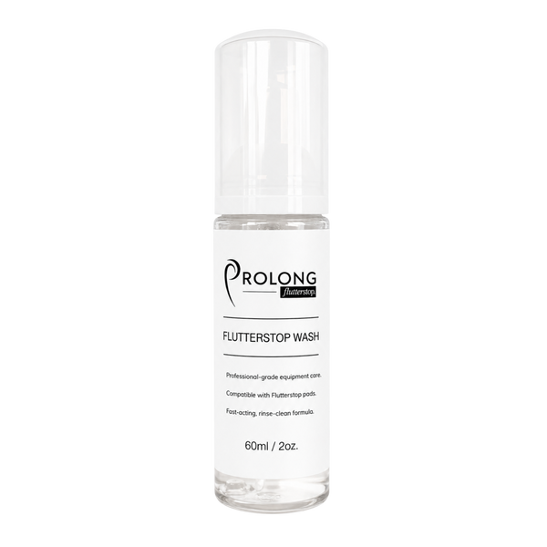 Flutterstop Wash by Prolong Lash US in a sleek minimal bottle resting on a textured champagne-toned silk cloth.