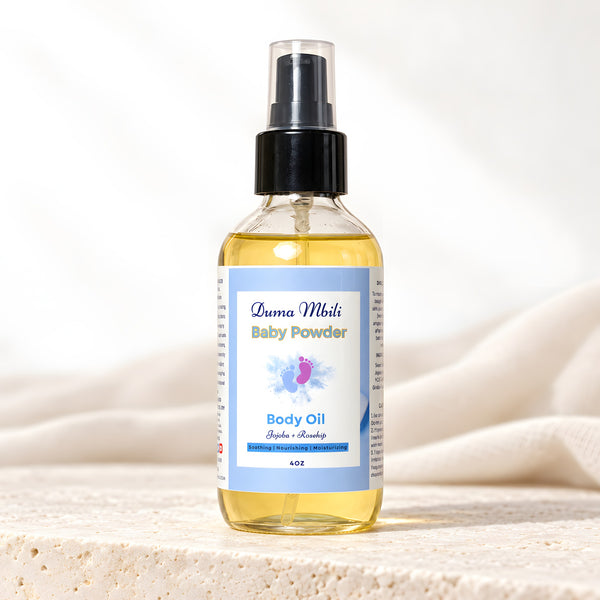 Duma Mbili Baby Powder Body Oil in a sleek glass bottle resting on a travertine surface with soft morning light.