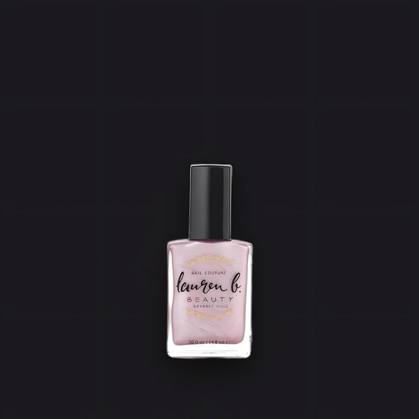 Lauren B. Beauty Beverly Hills Blush nail polish bottle in a sleek glass vessel resting on a neutral textured surface.