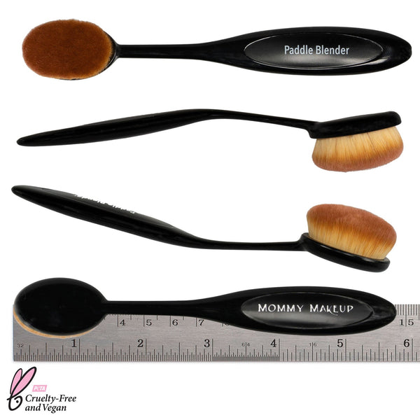 Mommy Makeup Paddle Blender Brush featuring a sleek, ergonomic handle resting on textured oatmeal-colored raw silk.