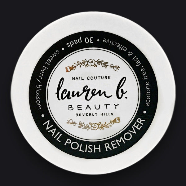 Lauren B. Beauty nail polish remover pads in a sleek, minimalist jar resting on a textured travertine surface.