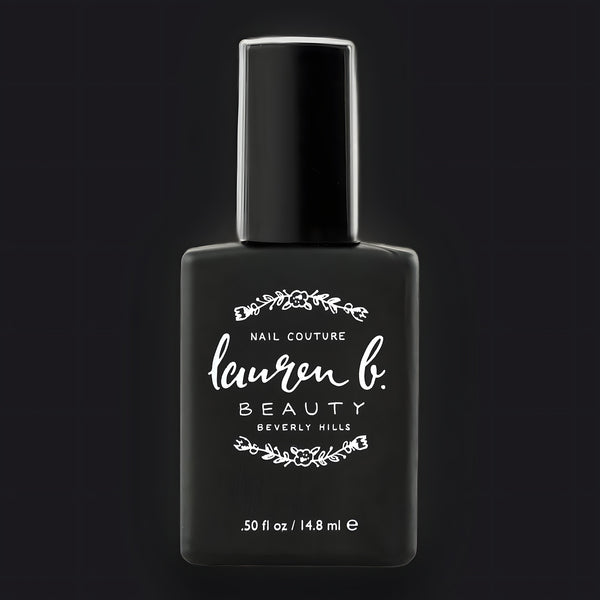 Lauren B. Beauty Light Activated GEL Topcoat in a sleek glass bottle resting on a textured travertine surface.
