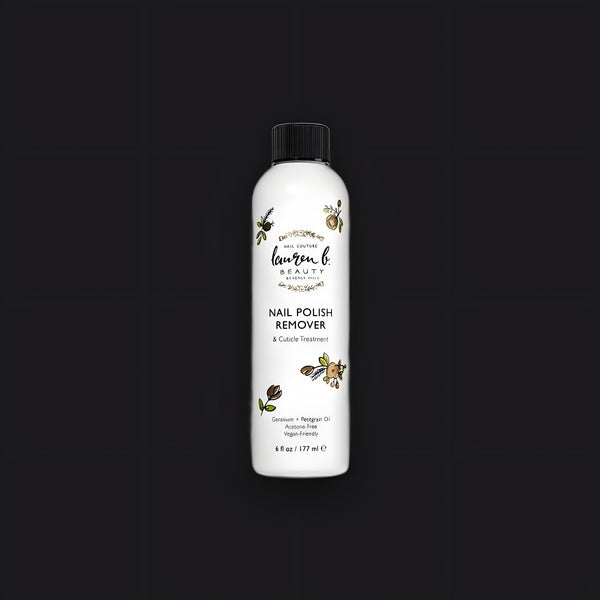 Lauren B. Beauty Liquid Nail Polish Remover and Cuticle Treatment in a minimalist clear glass bottle on travertine.
