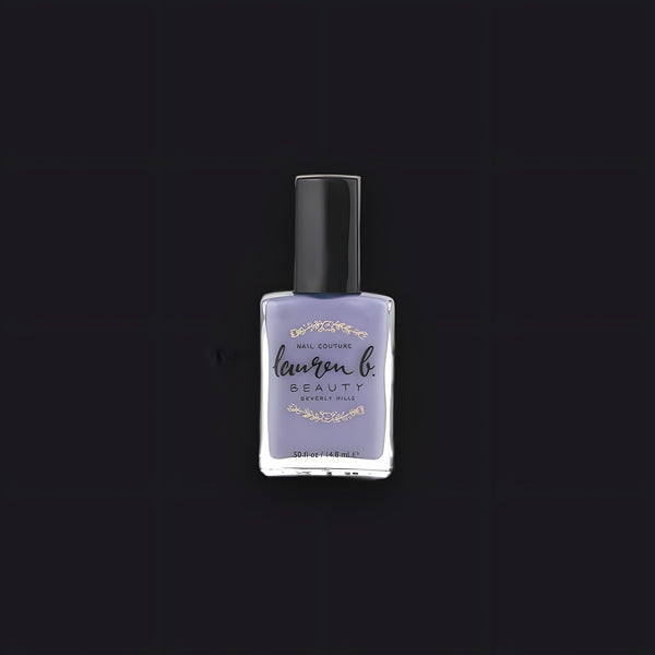 Lauren B. Beauty Meet Me on Melrose nail polish in a chic glass bottle resting on a textured travertine plinth.