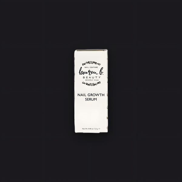 Lauren B. Beauty Nail Growth Serum in a glass bottle with a clean brush applicator resting on a smooth travertine plinth.