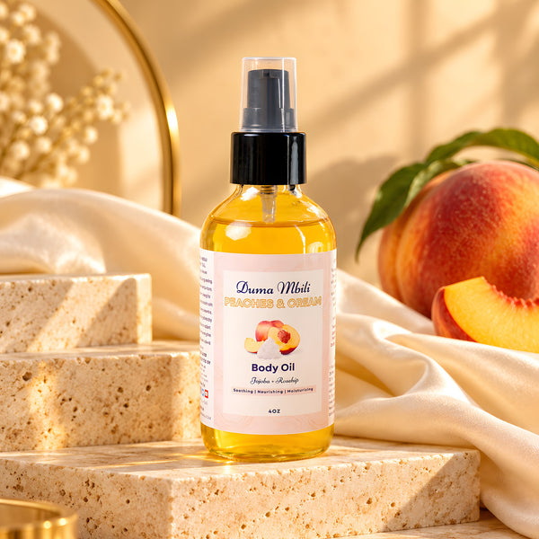 Adorn Collective Peaches & Cream Body Oil in a sleek glass bottle resting on a textured travertine plinth.