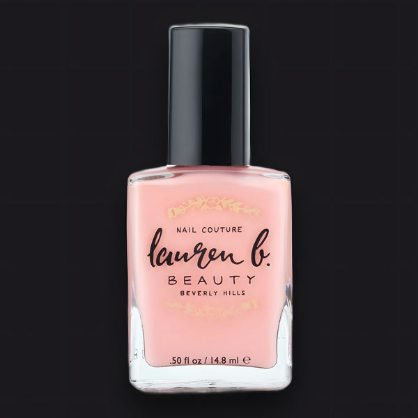 Clear glass bottle of Lauren B. Beauty Pfeiffer Beach Glow Vegan Nail Polish set against a warm luxury backdrop.