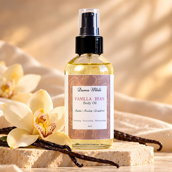 Adorn Collective Vanilla Bean Body Oil in a sleek amber glass apothecary bottle resting on a textured travertine plinth.